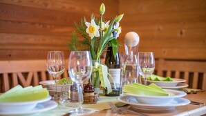 A wooden table set with plates, glasses, a bottle, and a vase with flowers. - Apartment "Ferienhaus Pichlerhof" with Mountain View, Shared Garden & Wi-Fi (Fundres)