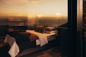 Une chambre à coucher avec un lit, une table de chevet et une vue sur l’océan.