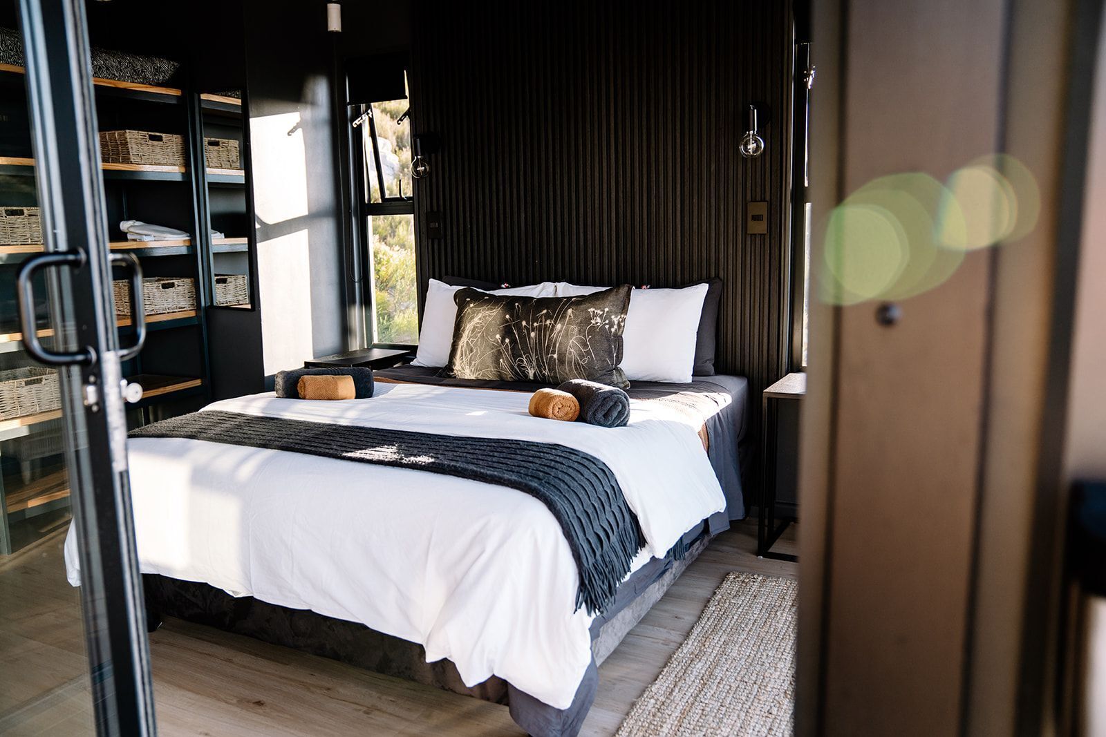 Une chambre à coucher moderne avec un lit, des tables de chevet, une fenêtre et des étagères intégrées avec des paniers.