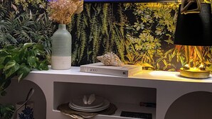 Una televisione con il logo Netflix, un vaso decorativo, un libro dal titolo 'At 100', una conchiglia, una lampada e una ciotola di popcorn.