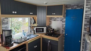 Une cuisine compacte équipée d’un four à micro-ondes, d’une cuisinière et d’une machine à café.