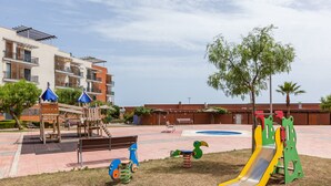 Ein Spielplatz mit Schaukeln, Rutschen und einer Kletteranlage.