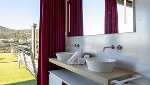 Ein Badezimmer mit zwei Waschbecken, einem Spiegel und Blick auf einen Balkon.