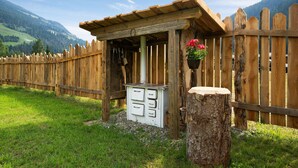 A rustic wooden structure with a sloped roof, a wooden fence, and a stone stump.