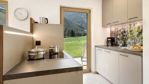 Een moderne keuken met uitzicht op een bebost landschap door een groot raam.