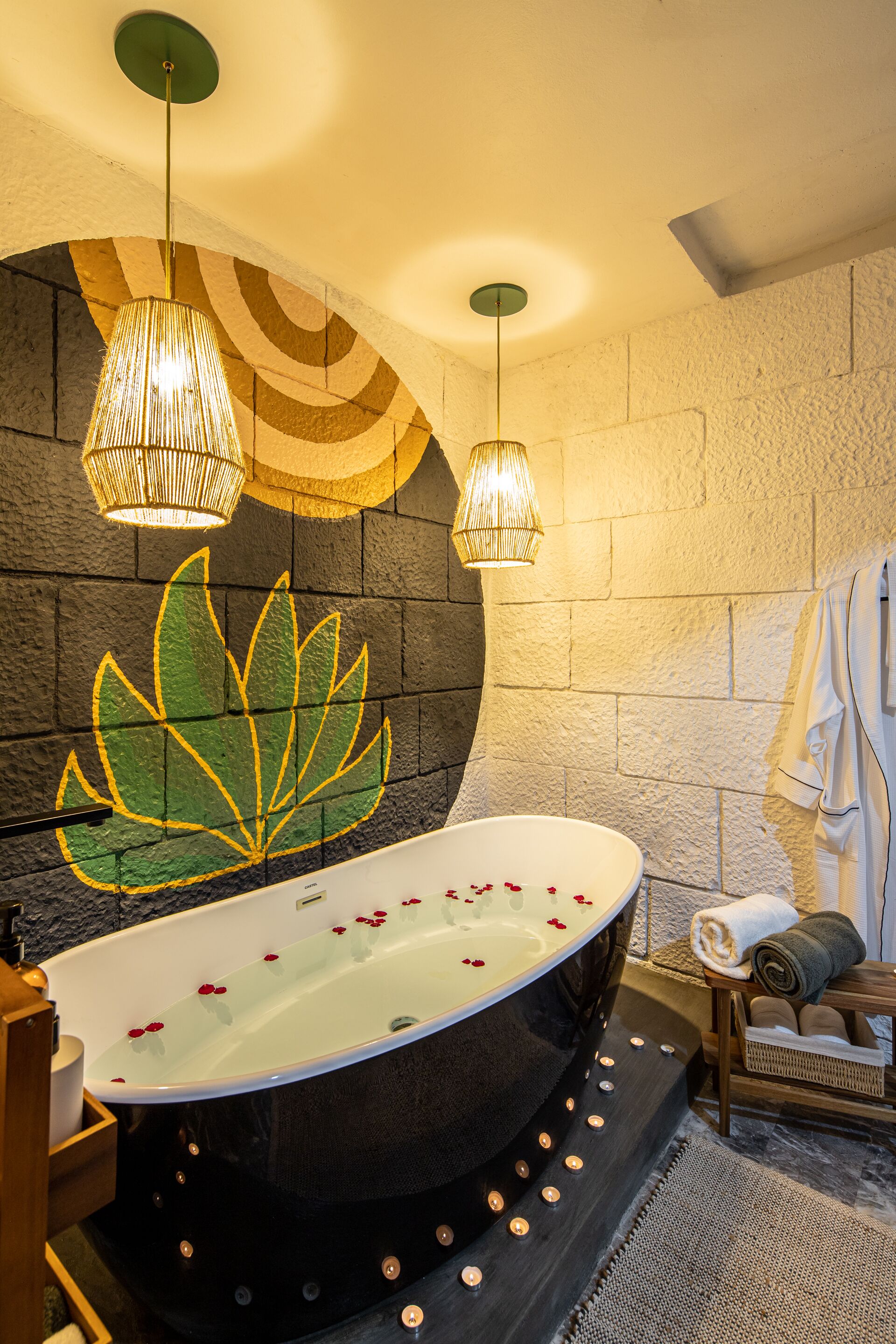 A modern bathroom with a freestanding bathtub, a large wall mural, and two hanging light fixtures.