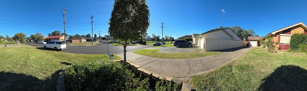 A suburban street with houses, cars parked along the side, and a mailbox in the foreground.