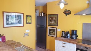 Eine Küche mit gelber Wand, einem Edelstahl-Kühlschrank, einem Herd und verschiedenen Küchengeräten.