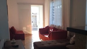 Una sala de estar con un sofá, un reposapiés y una mesita con una regleta eléctrica.
