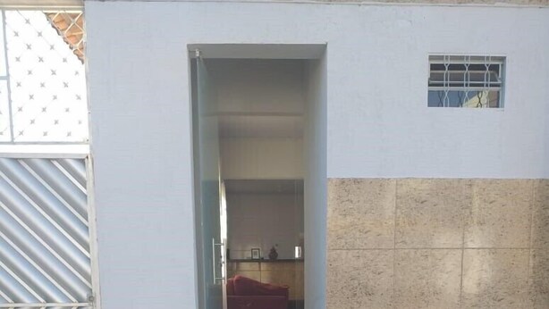 Un sendero lleva a una habitación con sofá rojo, piso de baldosas y una cocina parcialmente visible.
