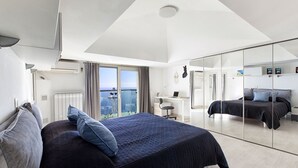 Ein modernes Schlafzimmer mit einem großen Bett, einem Schreibtisch und Blick auf die Stadt.