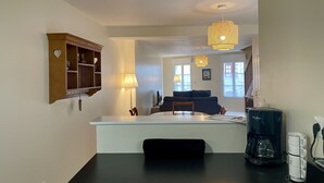 Ett modernt kök med en central köksö, en kaffebryggare och en matplats med en soffa och en lampa.
