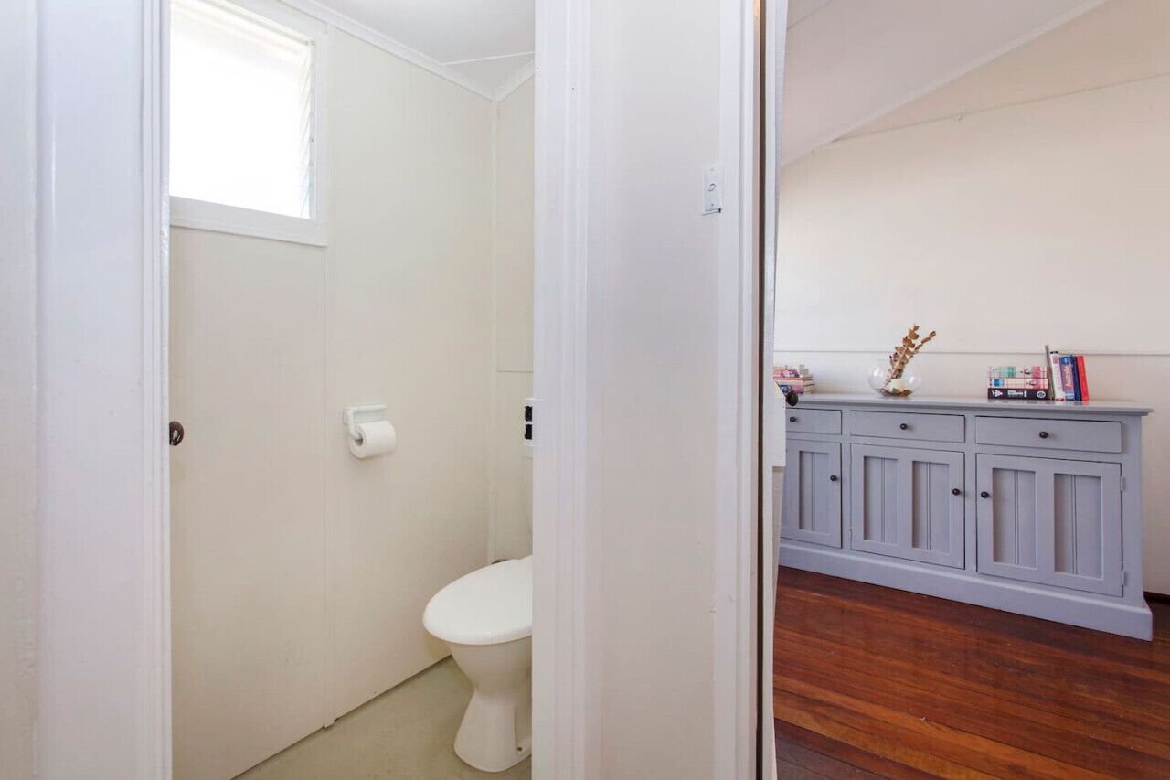 Une salle de bain comprenant des toilettes, une fenêtre et un meuble-lavabo avec des placards et un miroir.