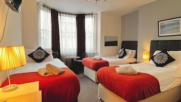 A hotel room with two beds, a TV, a desk, a chair, and a window with curtains.