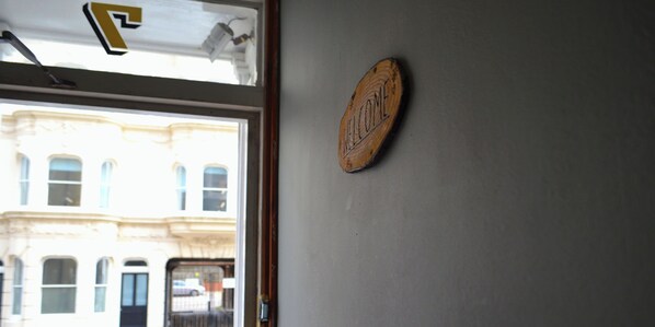 A door with a 'WELCOME' sign on the wall and a view of a building outside. - The Old Palace Guest House (Brighton)