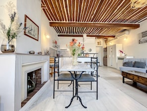 A dining area with a marble table, black chairs, and a wooden ceiling.