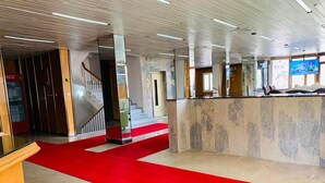 A hotel lobby with a red carpet, a reception desk, and a staircase leading to another floor. - mardin konağı (Mardin)