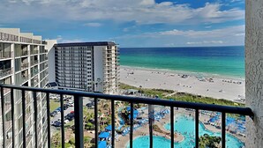 Ein Hotelbalkon mit Blick auf einen Strand und einen Poolbereich.