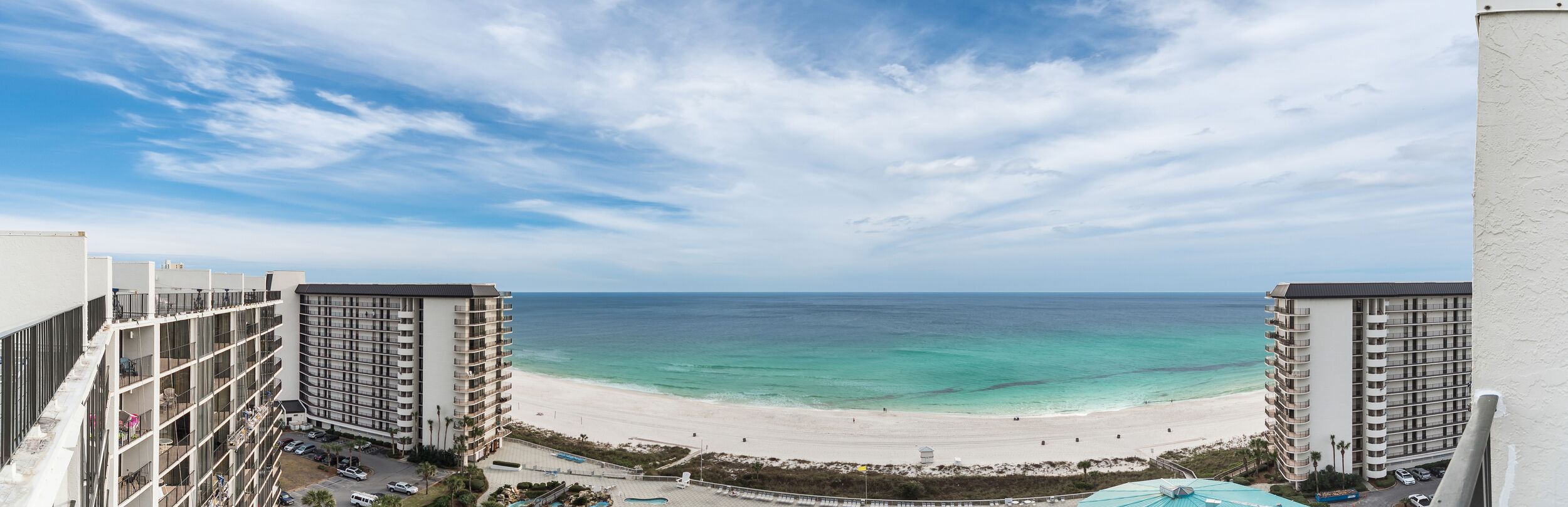 A beachfront hotel with multiple floors, a pool, and a view of the ocean.