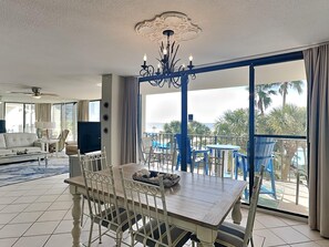 Relax in this stylish living area with a dining table for four, chandelier, and sliding glass door leading to a balcony with ocean views.