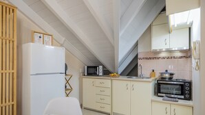 A compact kitchen with a microwave, oven, and refrigerator. There is a dining table with plates and cutlery. - City Suite - The Loft in Kefalonia (argostoli)