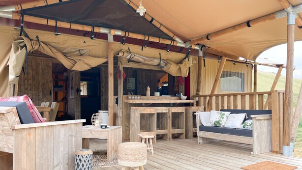 A wooden deck with a covered seating area, including a sofa and a table. - Hitton Séjours Nature (Biran)