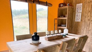 A wooden dining table with chairs, a black and white candle holder, and a window with a view of greenery. - Hitton Séjours Nature (Biran)