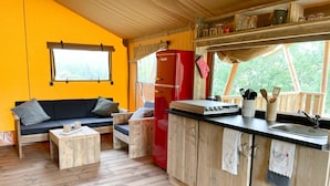 A compact kitchen with a red refrigerator, wooden cabinets, and a black countertop. - Hitton Séjours Nature (Biran)