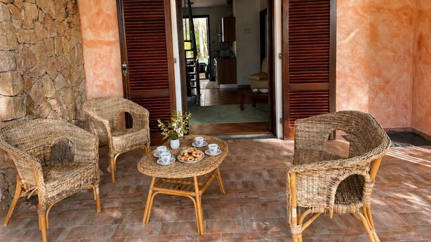An outdoor seating area with wicker furniture, a table with cups and pastries, and a stone wall. - New villa near the beach, clima, BBQ, WI-FI , garden (San Pietro a Mare)