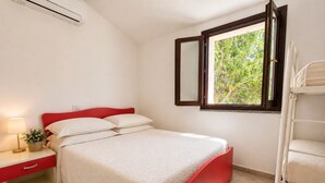 A bedroom with a bed, bedside table, lamp, and a window with a view of greenery. - New villa near the beach, clima, BBQ, WI-FI , garden (San Pietro a Mare)