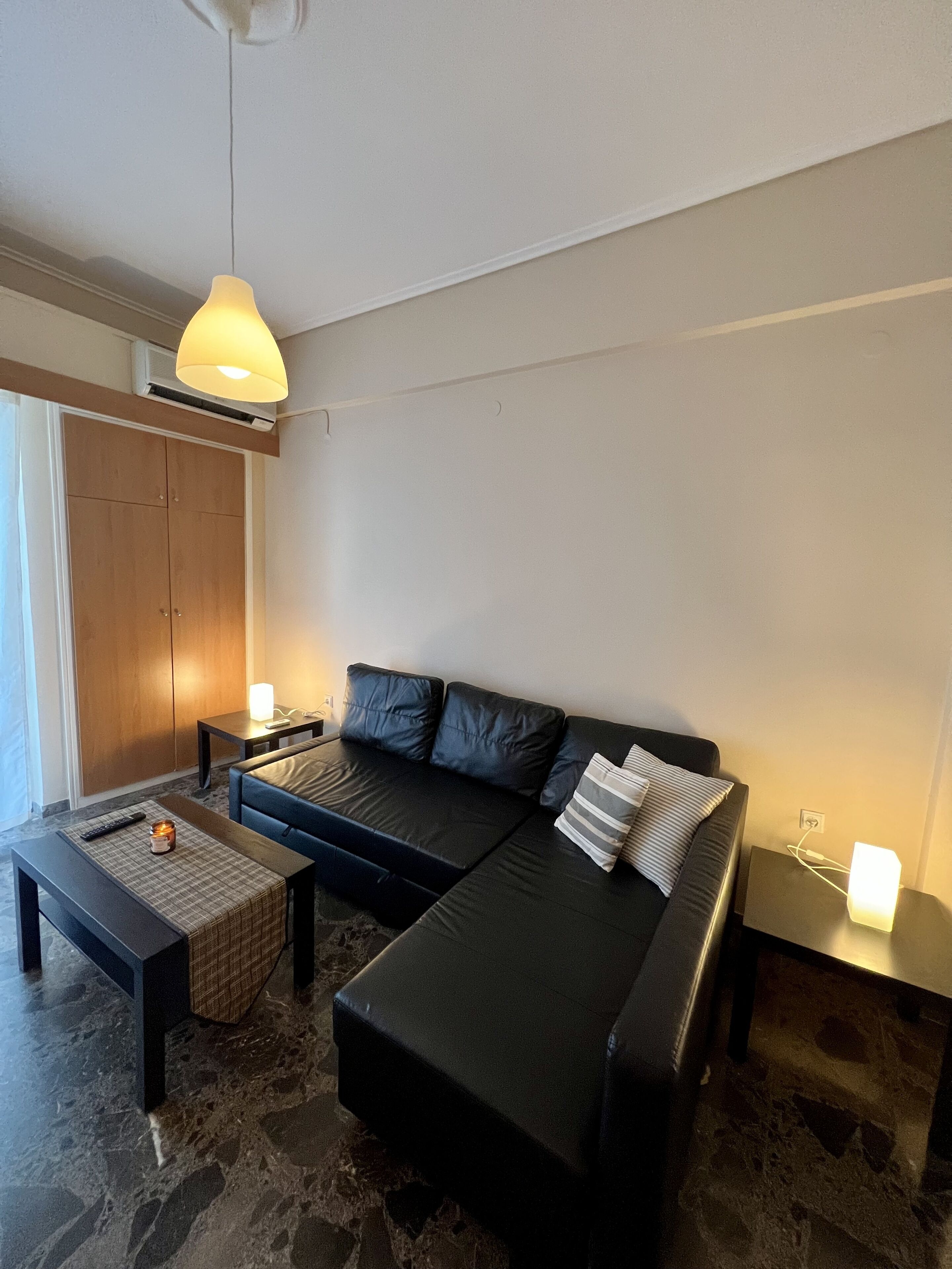 Un salon moderne avec un canapé noir, une table basse et un luminaire suspendu.