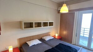 Un dormitorio moderno con una cama grande, una mesita de noche con lámpara, estantería empotrada y vistas al exterior a través de una puerta corredera.