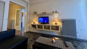 Una sala de estar con televisor, dos lámparas, un radiador y un sofá.