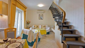 Un espace de vie compact comprenant un coin repas, un canapé, un escalier et une cuisine.