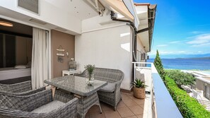 Ein Balkon mit Korbmöbeln, einem kleinen Tisch und einem Blumentopf.