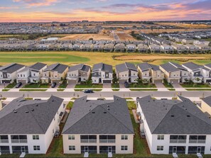 A residential area with modern houses, a golf course in the background, and a clear sky.