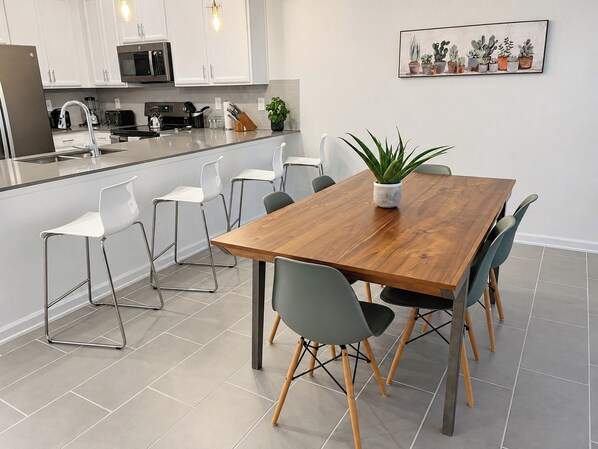 A modern kitchen with white cabinets, a microwave, and a coffee machine.