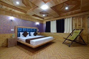 A room with a bed, a wooden ceiling, a herringbone floor pattern, and a wooden cabinet.