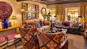 Una sala de estar acogedora con muebles estampados, un jarrón decorativo grande y obras de arte enmarcadas en las paredes.