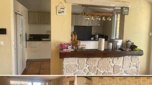 A kitchen with a stone island, a dining area with a table and chairs, and a living room with a sofa and a coffee table. - Le Cabanon (Portel-des-Corbières)