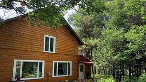 Eine Holzhütte mit zwei Fenstern, einer Tür und einer kleinen Veranda.