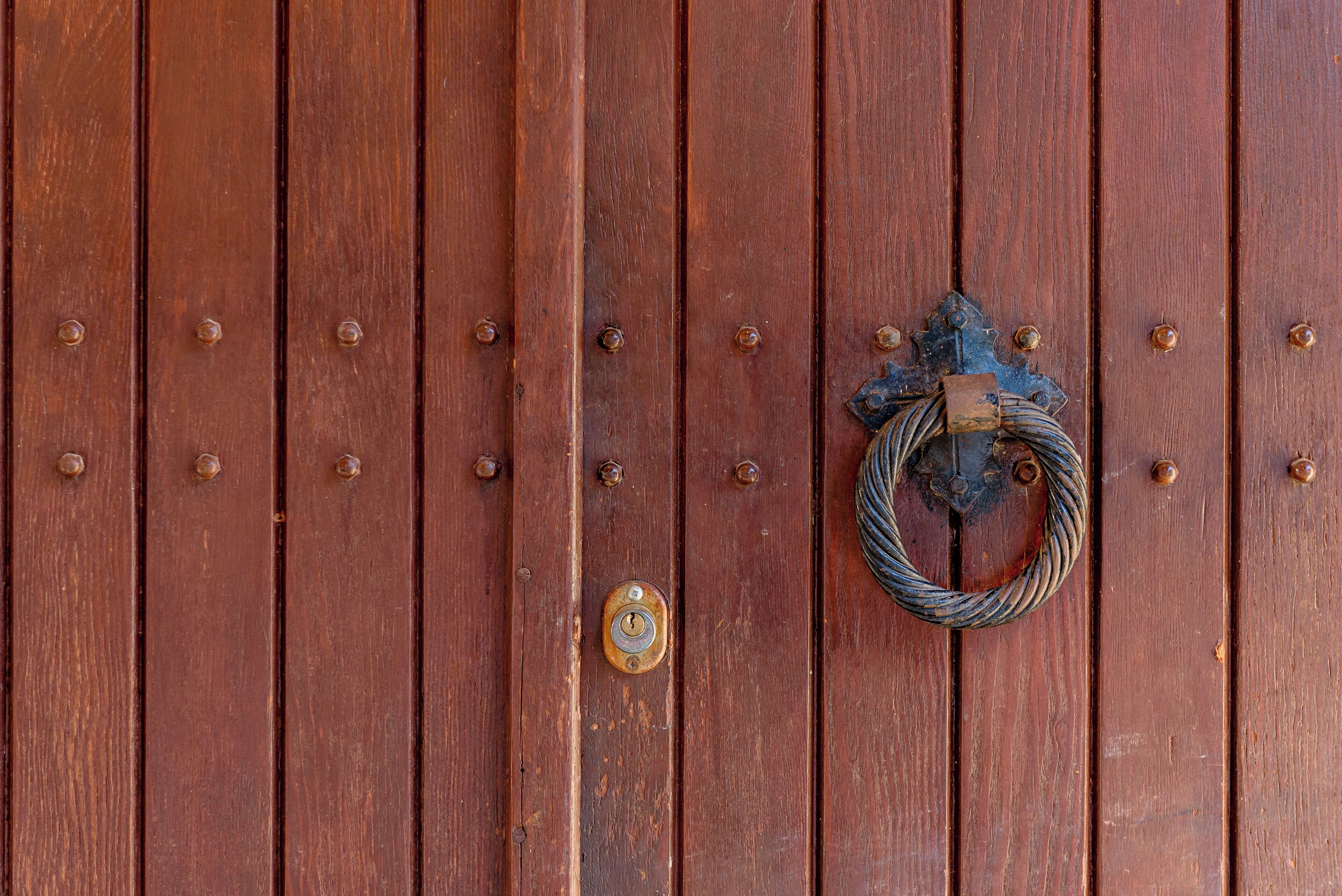 A wooden door with a metal knocker and a keyhole.
