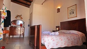 Un dormitorio con una cama de madera, un tocador, un espejo y una lámpara de pared.