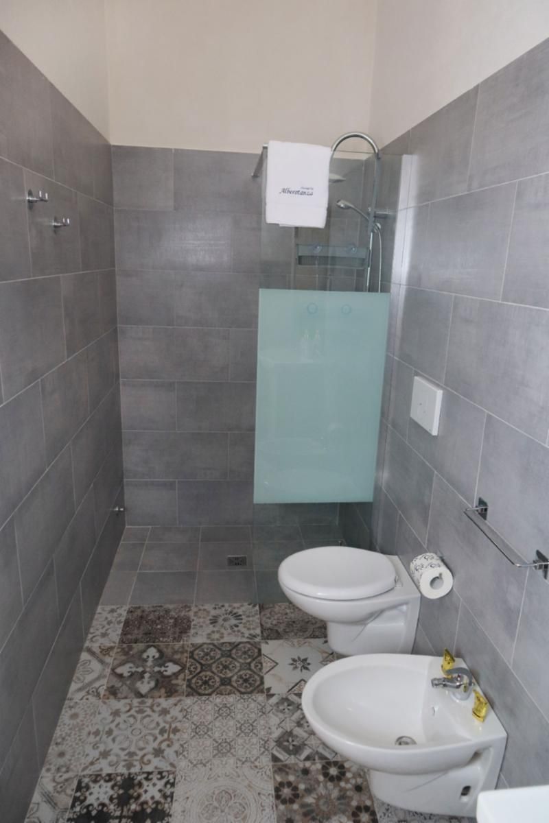 Een badkamer met een douche, toilet en een hygiëneschuimer.