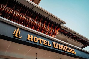 A hotel sign with the name "HOTEL LUMIERE" in large golden letters on a dark facade. - Hotel Lumiere (Ambalapuzha)