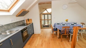 A kitchen with a skylight, a dining area with a checkered tablecloth, and a view through a glass door. - Green Grove Barn (Carmarthen)
