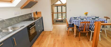 A kitchen with a skylight, a dining area with a checkered tablecloth, and a view through a glass door.