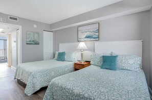 A bedroom with two beds, a nightstand, a lamp, and a painting of a sailboat. - Beautiful Oceanfront 1 Bedroom Condo at Seawatch Resort (Myrtle Beach)