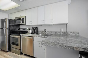 A modern kitchen with stainless steel appliances, white cabinetry, and a granite countertop. - Beautiful Oceanfront 1 Bedroom Condo at Seawatch Resort (Myrtle Beach)