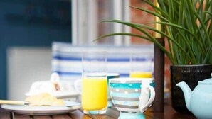 A breakfast setting with a plate of food, a glass of orange juice, and a striped mug on a wooden table. - The Nets - Fantastic 3 bedroom house with parking (Filey)